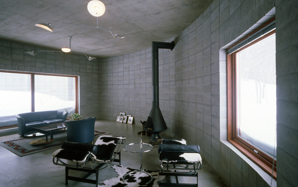 Fernseherloses, Offenes Industrial Wohnzimmer mit grauer Wandfarbe, Betonboden und Hängekamin in Sapporo