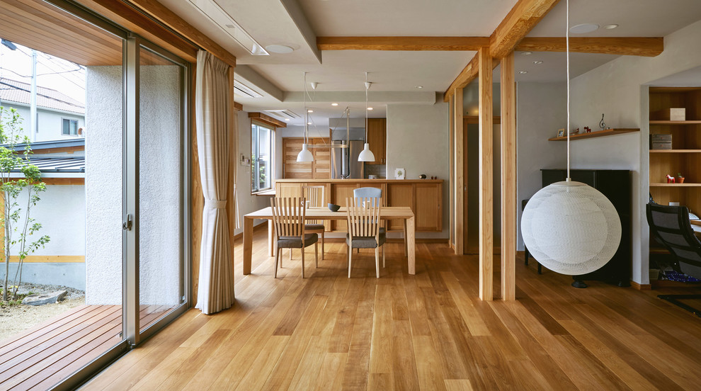 Réalisation d'un salon asiatique ouvert avec un sol en bois brun, un mur blanc et un sol marron.
