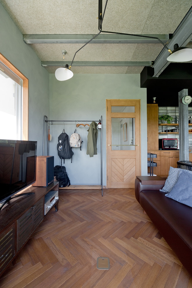 Ejemplo de salón abierto urbano de tamaño medio sin chimenea con paredes grises, suelo de madera en tonos medios, televisor independiente y suelo marrón