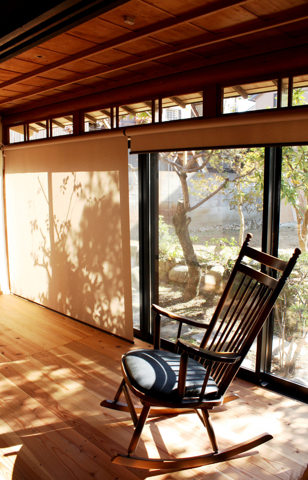 Foto de salón abierto de estilo zen pequeño con paredes beige, suelo de madera clara, estufa de leña, marco de chimenea de yeso y suelo beige