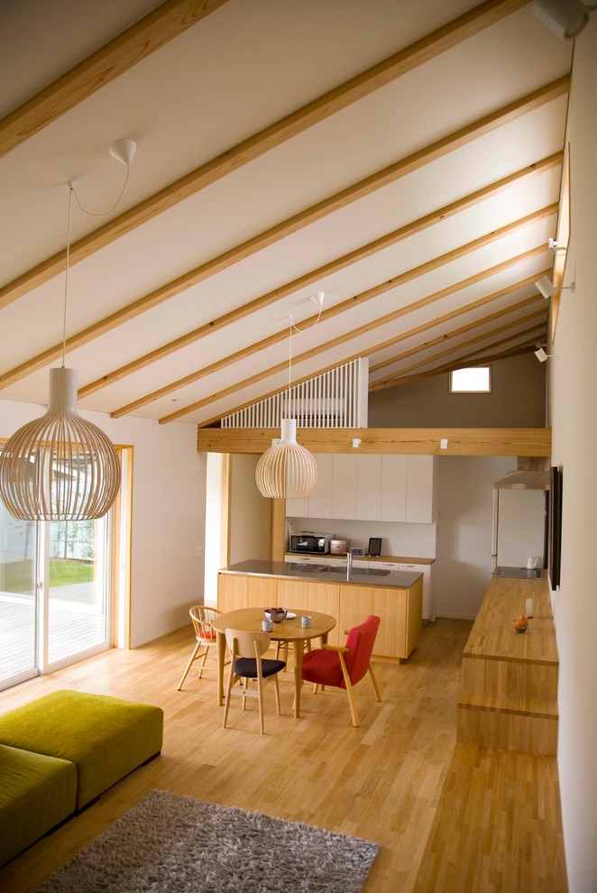 Modelo de salón abierto contemporáneo sin chimenea con paredes blancas y suelo de madera en tonos medios