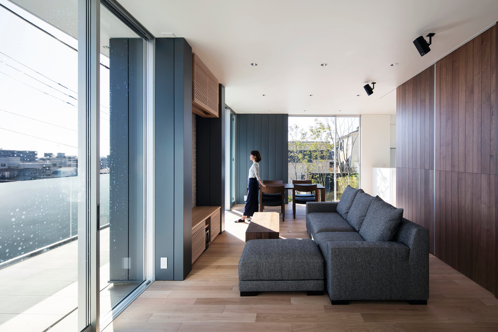 Immagine di un soggiorno minimalista di medie dimensioni e aperto con pareti marroni, pavimento in compensato, nessun camino e TV autoportante