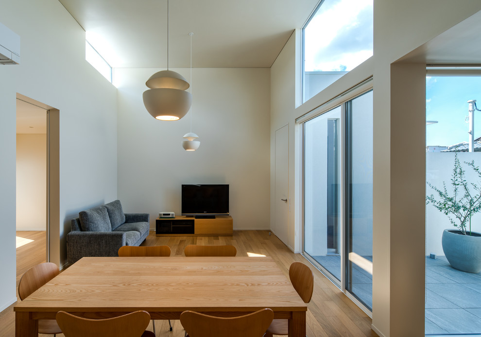 Modelo de salón abierto minimalista con paredes blancas, suelo de contrachapado, suelo marrón y televisor independiente