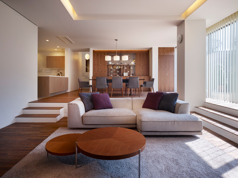 Offenes Modernes Wohnzimmer mit weißer Wandfarbe, dunklem Holzboden und braunem Boden in Tokio