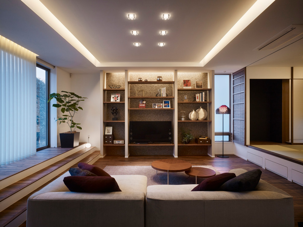 Стильный дизайн: гостиная комната в современном стиле с белыми стенами, темным паркетным полом и отдельно стоящим телевизором - последний тренд