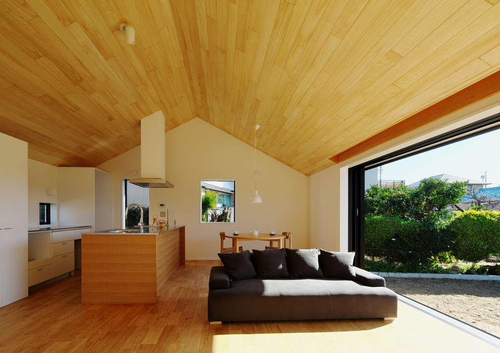 Cette image montre un salon minimaliste ouvert avec un mur blanc, un sol en bois brun, aucune cheminée et un sol beige.
