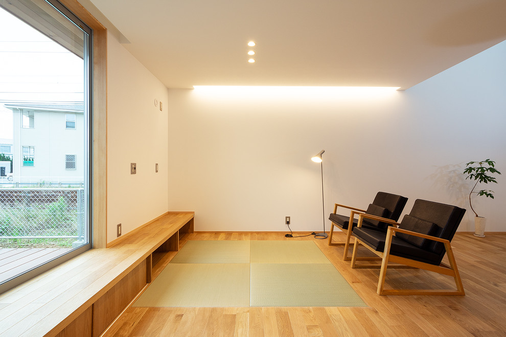 Offenes Asiatisches Wohnzimmer mit weißer Wandfarbe, braunem Holzboden, TV-Wand und braunem Boden in Sonstige