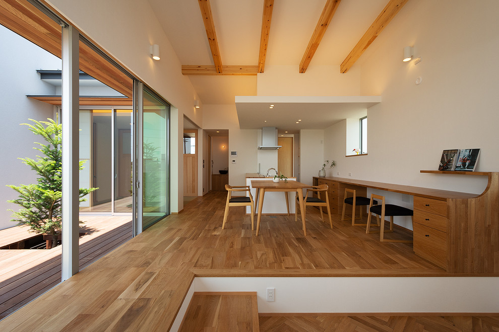 Idéer för att renovera ett minimalistiskt allrum med öppen planlösning, med vita väggar, mellanmörkt trägolv och brunt golv
