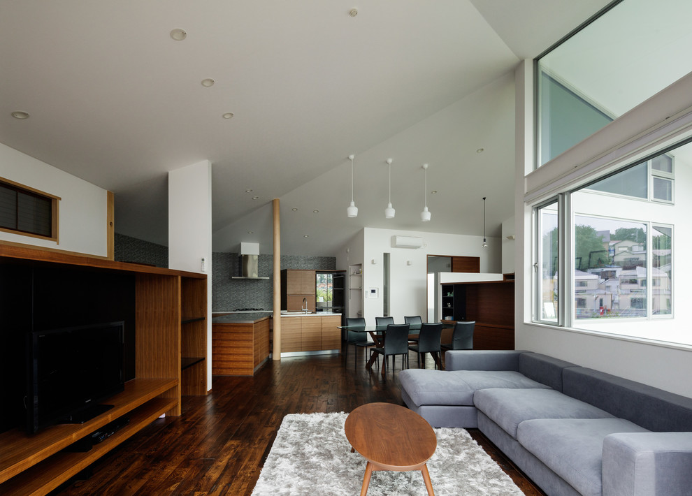 Идея дизайна: открытая гостиная комната в восточном стиле с белыми стенами, темным паркетным полом, отдельно стоящим телевизором и коричневым полом