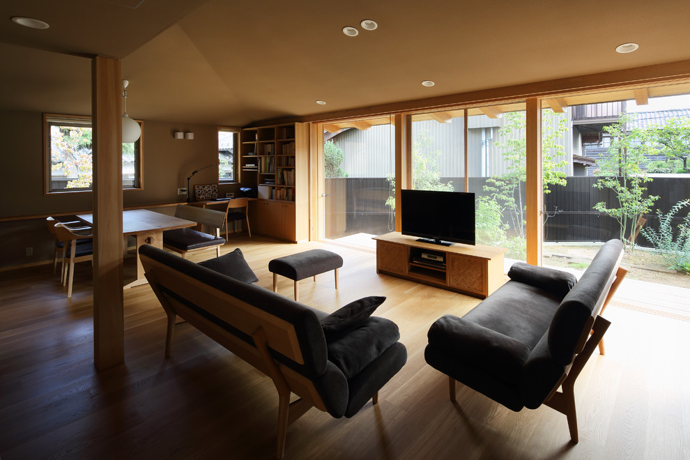 Trendy open concept medium tone wood floor living room photo in Kyoto with beige walls, no fireplace and a tv stand