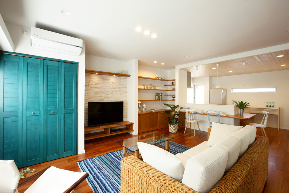 Exempel på ett exotiskt vardagsrum, med vita väggar, mellanmörkt trägolv, en fristående TV och brunt golv
