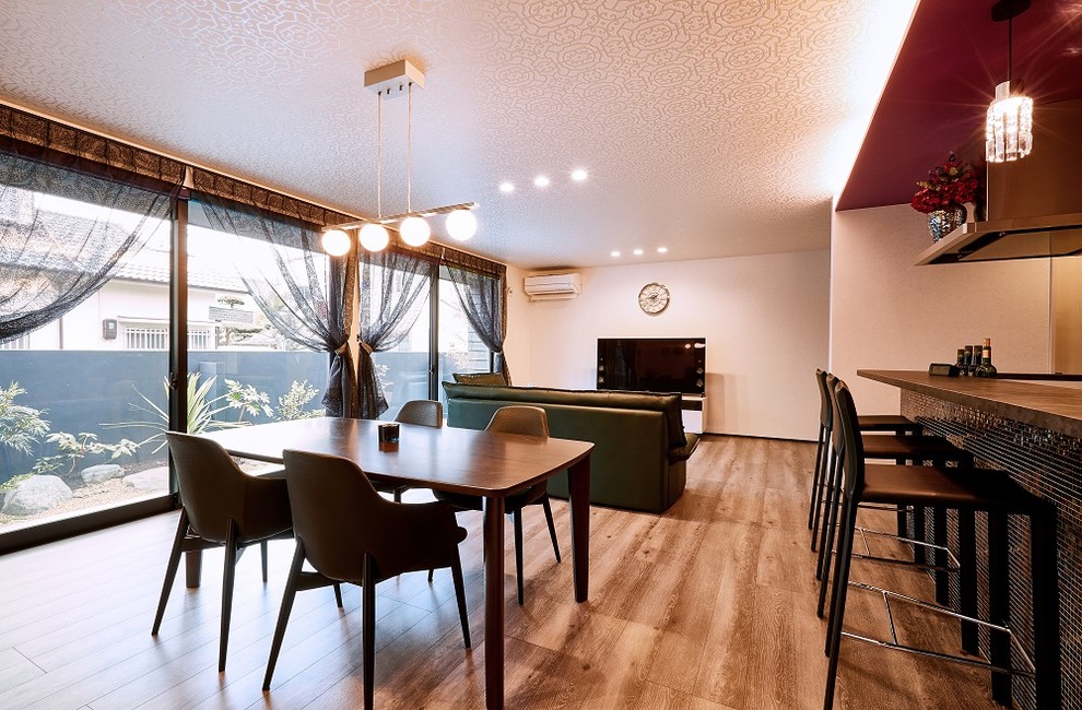 На фото: открытая гостиная комната в стиле модернизм с домашним баром, белыми стенами, полом из фанеры, отдельно стоящим телевизором и коричневым полом без камина с