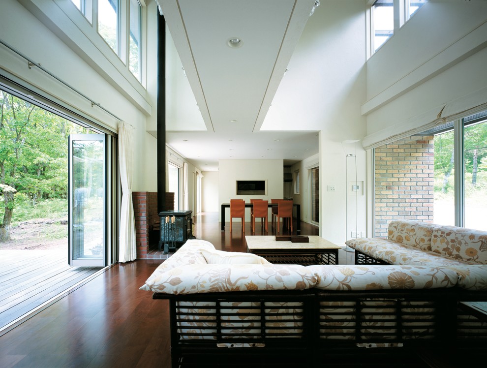 Idee per un soggiorno design con pareti bianche, parquet scuro, stufa a legna e cornice del camino in mattoni
