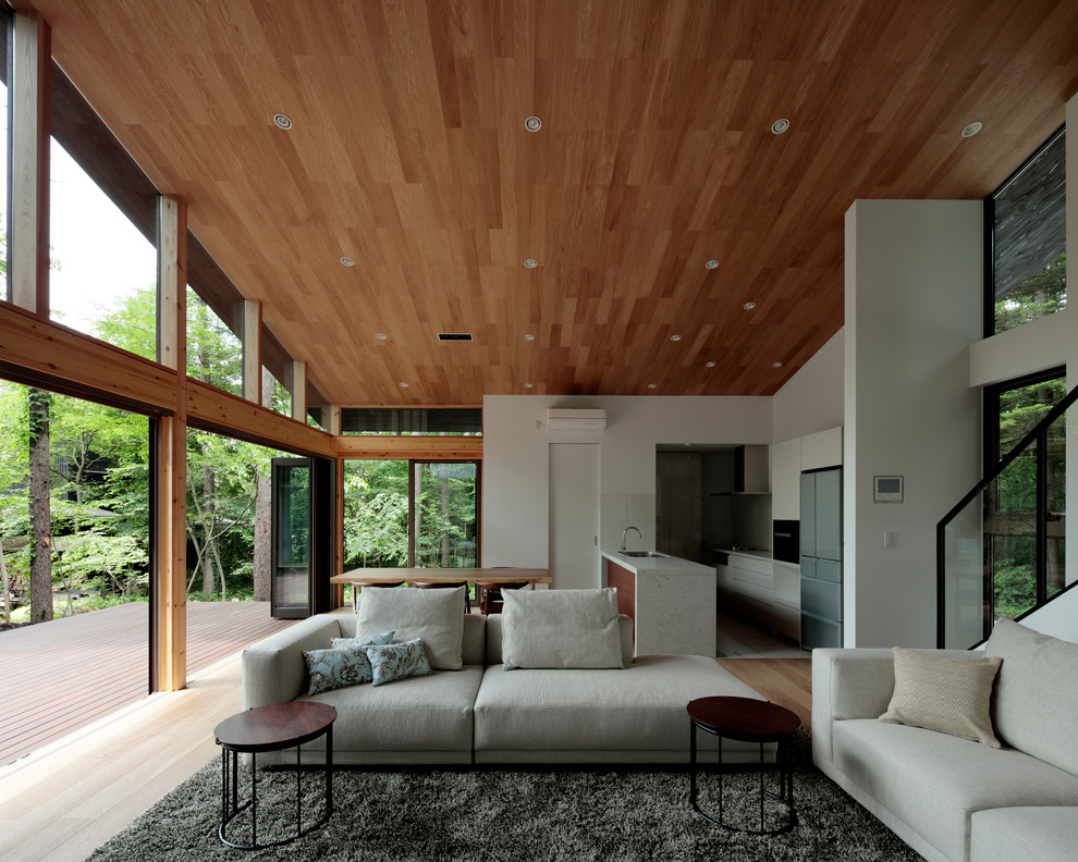 Imagen de salón abierto minimalista con paredes blancas, suelo de madera clara y suelo beige