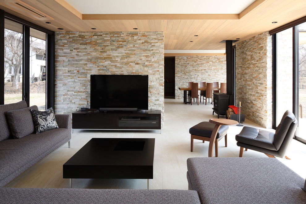 Пример оригинального дизайна: изолированная гостиная комната в стиле модернизм с бежевыми стенами, печью-буржуйкой и отдельно стоящим телевизором