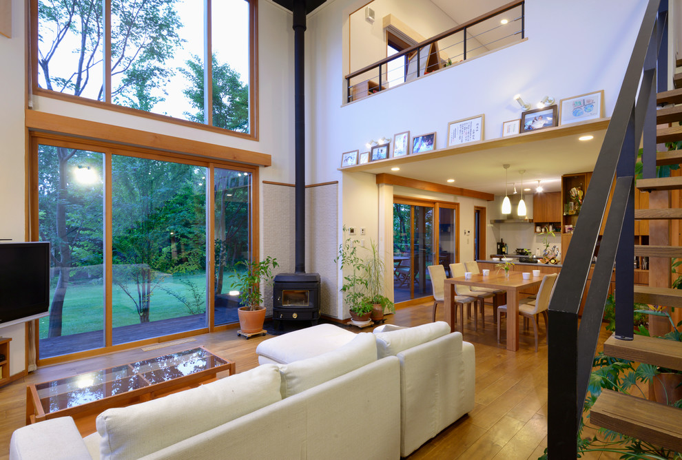 Immagine di un soggiorno design con pareti bianche, pavimento in legno massello medio e stufa a legna