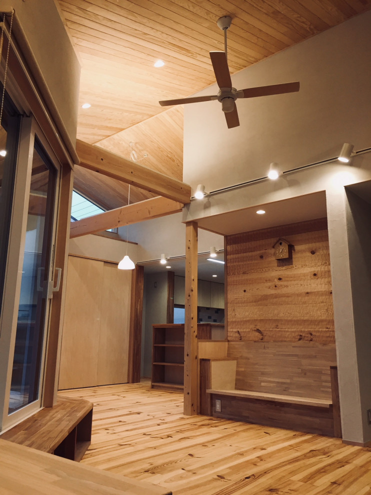 На фото: открытая гостиная комната среднего размера в скандинавском стиле с с книжными шкафами и полками, белыми стенами, светлым паркетным полом и деревянным потолком