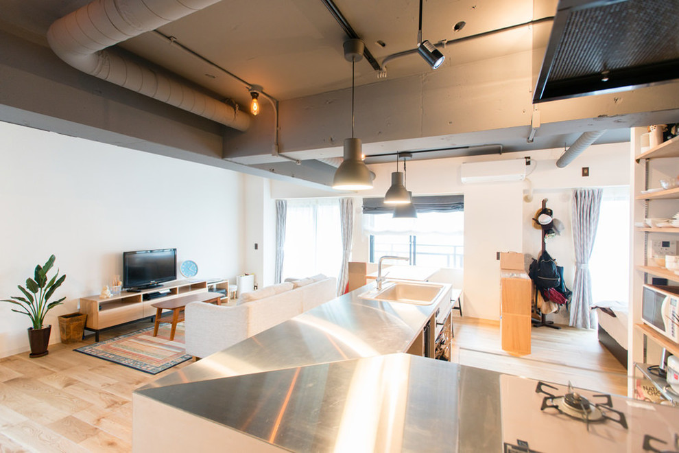 Aménagement d'un salon industriel de taille moyenne et ouvert avec un mur blanc, parquet clair, un téléviseur indépendant et un sol beige.