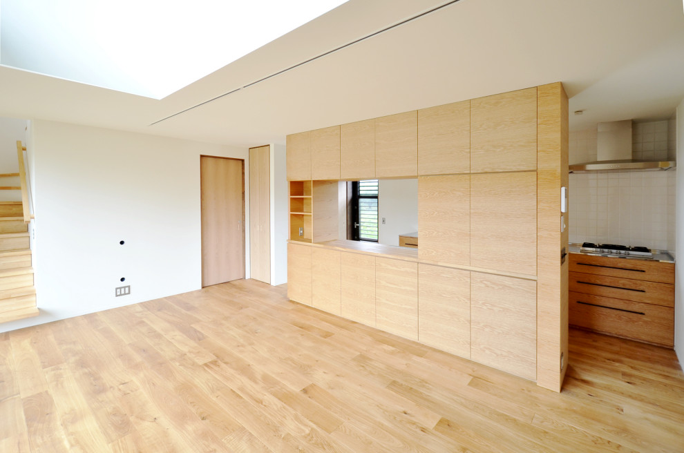 Exempel på ett stort nordiskt allrum med öppen planlösning, med en hemmabar, vita väggar, mellanmörkt trägolv, en väggmonterad TV och brunt golv