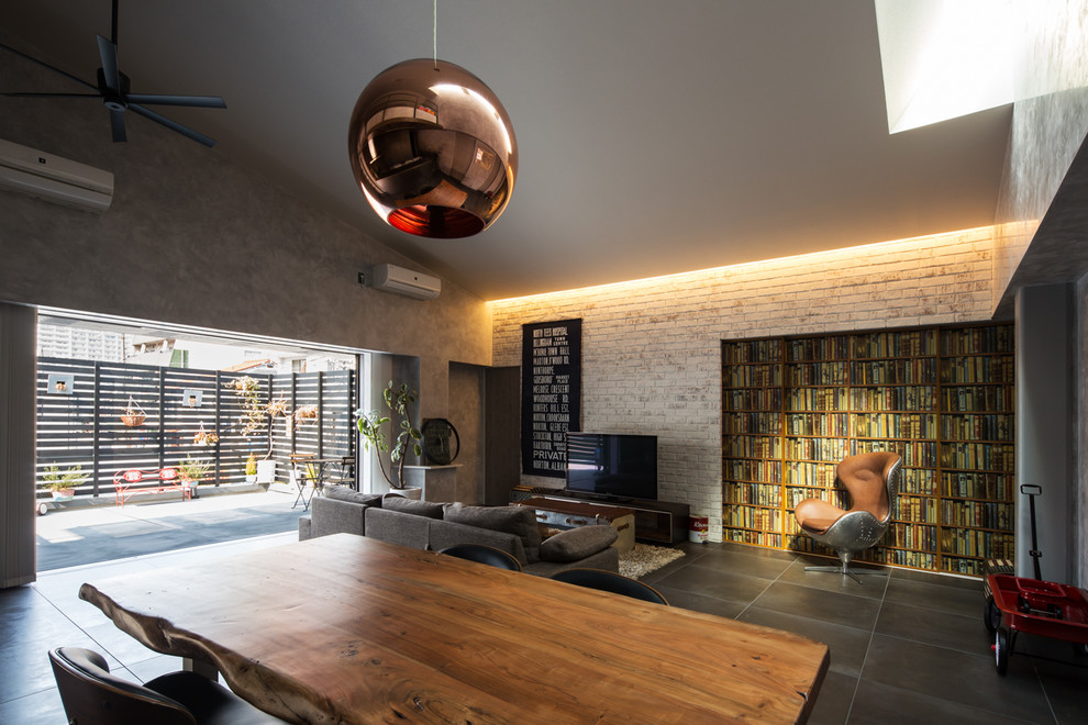 Offenes Uriges Wohnzimmer mit grauer Wandfarbe, freistehendem TV und schwarzem Boden in Osaka