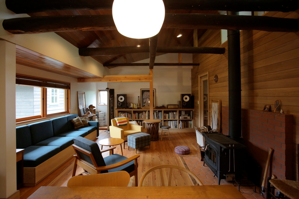 Foto de salón abierto de estilo zen de tamaño medio sin televisor con paredes blancas, suelo de madera en tonos medios, estufa de leña, marco de chimenea de ladrillo, madera y madera