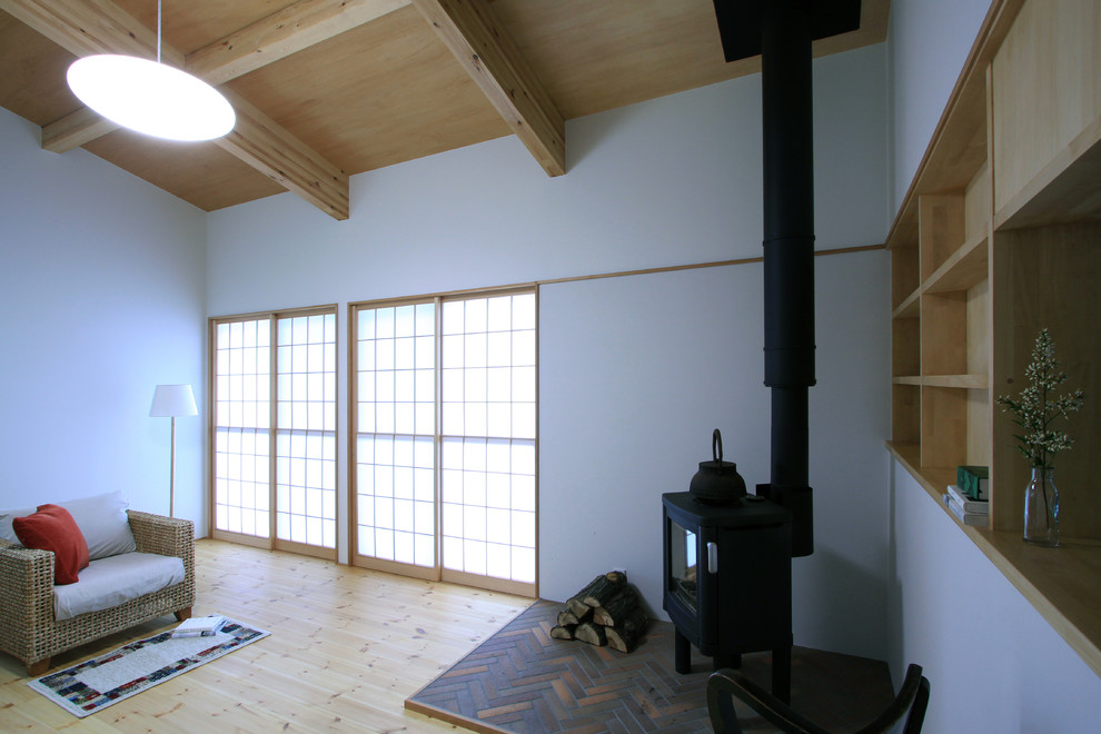 Idées déco pour un salon asiatique ouvert avec un sol en bois brun, un poêle à bois et un manteau de cheminée en brique.