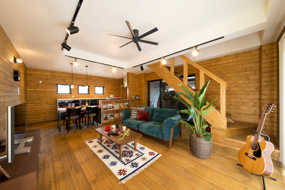 Photo of a world-inspired living room in Other with brown walls, medium hardwood flooring, a freestanding tv and brown floors.