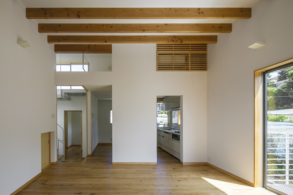Diseño de salón abierto de estilo zen de tamaño medio sin chimenea con paredes blancas, suelo de contrachapado, televisor independiente y suelo marrón