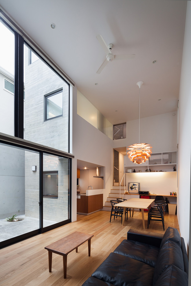 Modern formal open plan living room in Tokyo with white walls, medium hardwood flooring and brown floors.