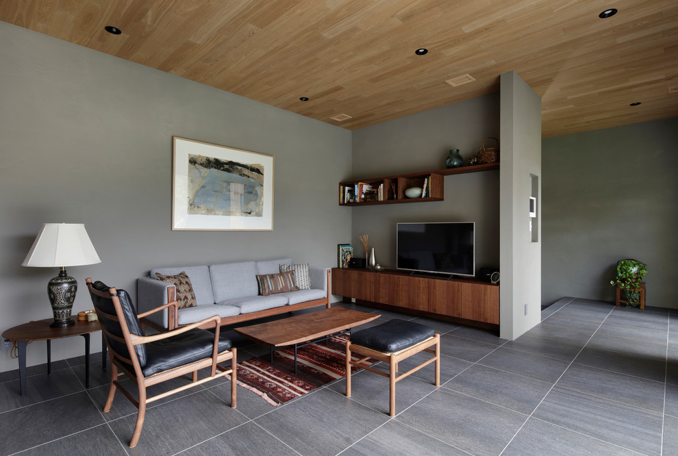 На фото: открытая гостиная комната в восточном стиле с серыми стенами, отдельно стоящим телевизором и серым полом