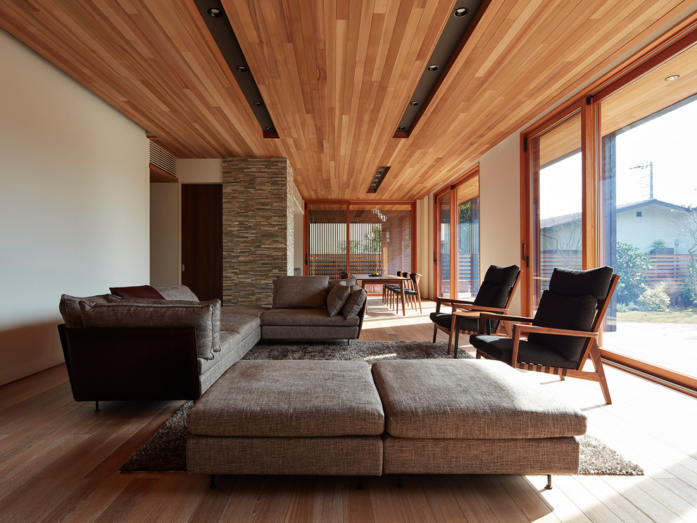 Modelo de salón abierto de estilo zen con paredes blancas, suelo de madera clara y suelo marrón
