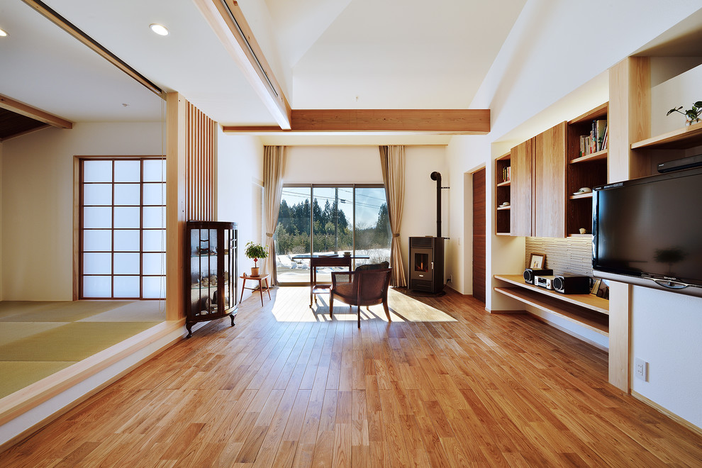 Cette photo montre un salon asiatique ouvert avec un mur blanc, un sol en bois brun, un poêle à bois et un sol marron.