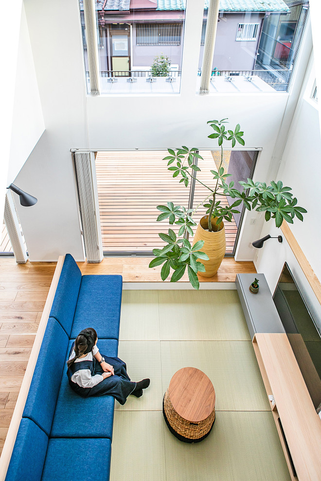 Esempio di un soggiorno minimal aperto con pareti bianche, pavimento in tatami, nessun camino e TV a parete