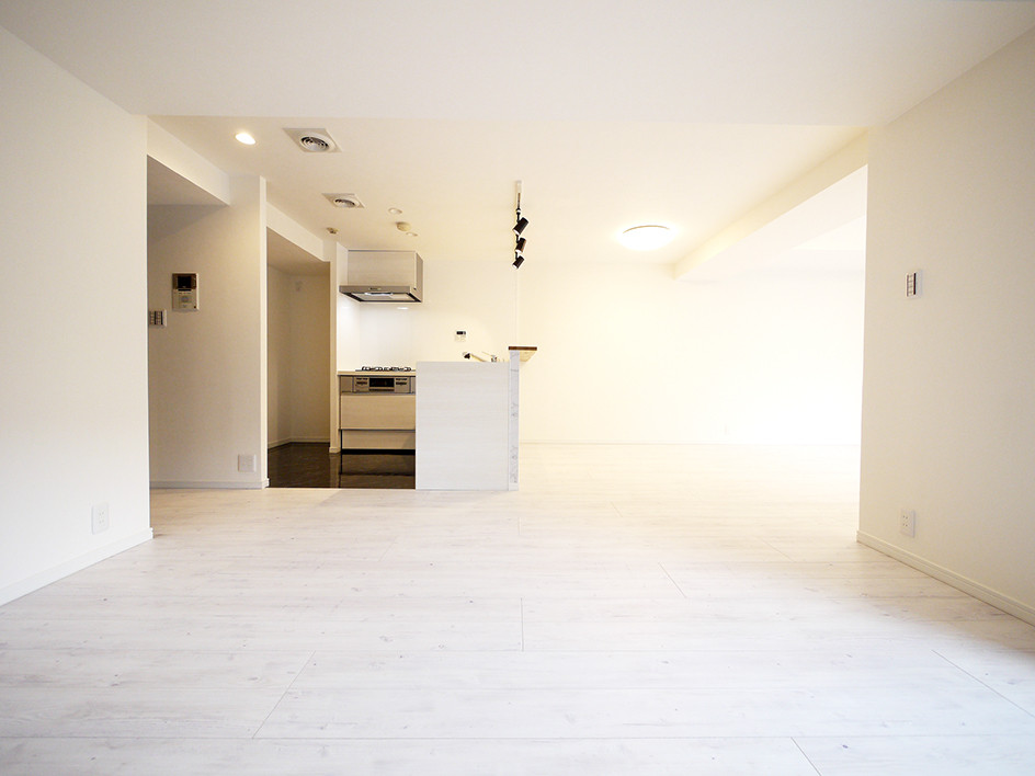 Modern inredning av ett allrum med öppen planlösning, med vita väggar, plywoodgolv och vitt golv
