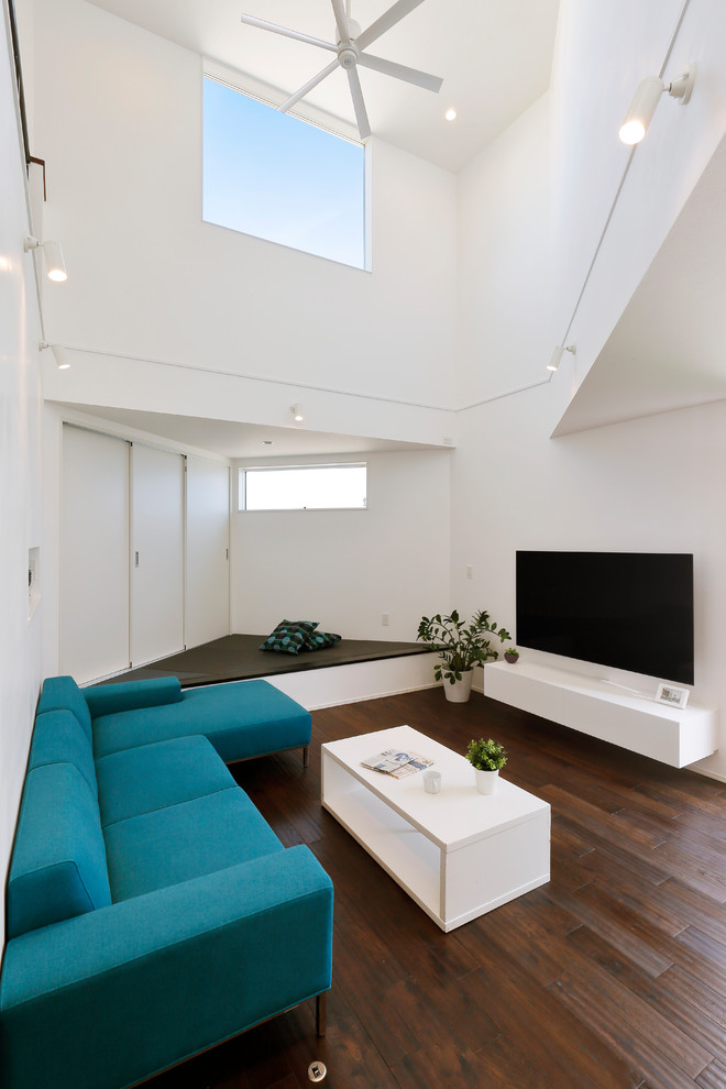 Esempio di un soggiorno minimalista aperto con pareti bianche, parquet scuro, TV a parete e pavimento marrone