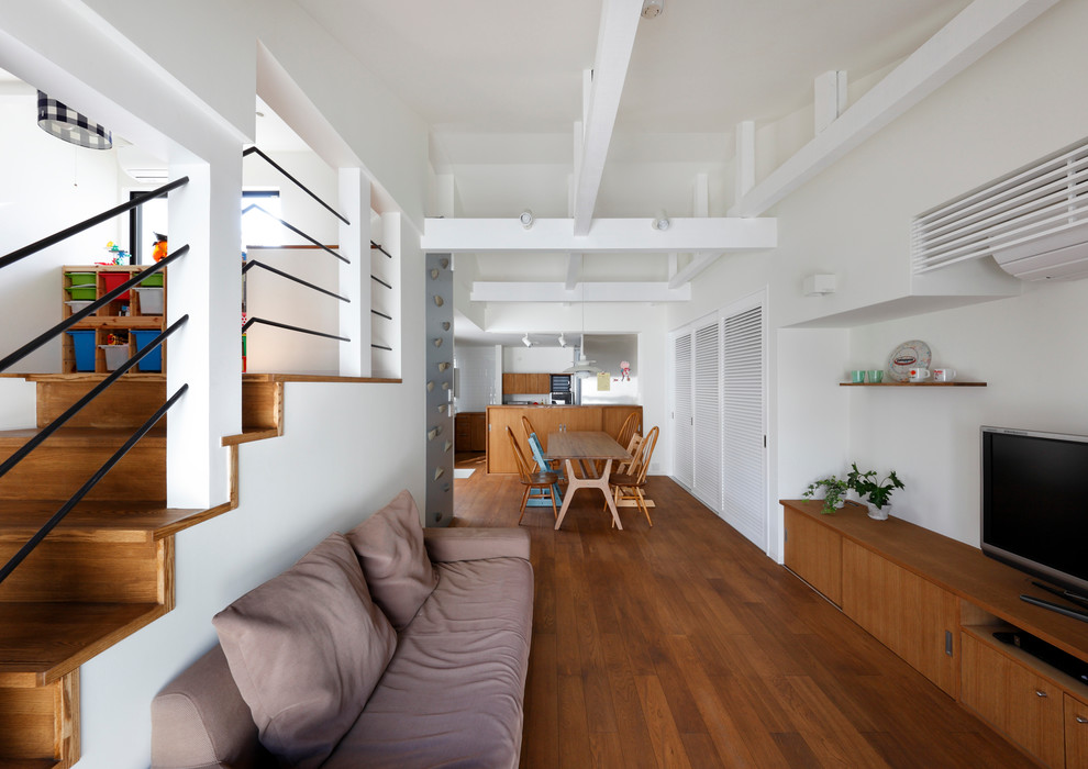 Diseño de salón abierto de estilo zen con paredes blancas, suelo de madera en tonos medios y televisor independiente