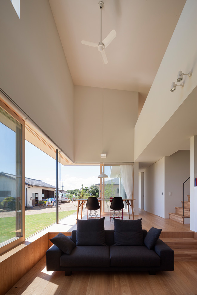 Offenes Modernes Wohnzimmer mit weißer Wandfarbe, braunem Holzboden und braunem Boden in Sonstige