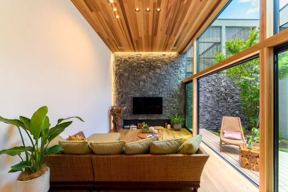 Idée de décoration pour un salon asiatique ouvert avec un mur multicolore, un sol en bois brun, un téléviseur fixé au mur et un sol marron.