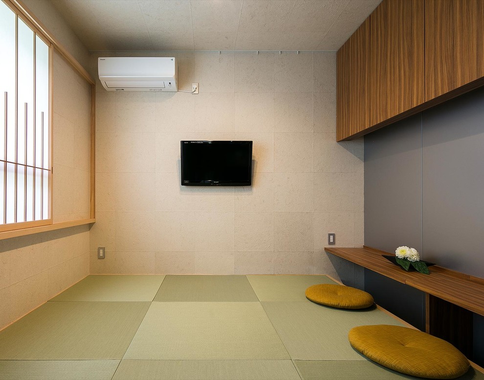 This is an example of a world-inspired enclosed living room with beige walls, tatami flooring, a wall mounted tv and green floors.