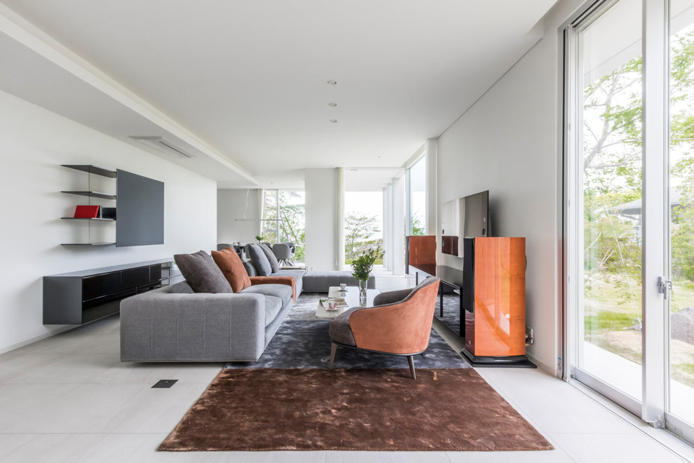 This is an example of a modern open plan living room with white walls, no fireplace, a wall mounted tv and beige floors.