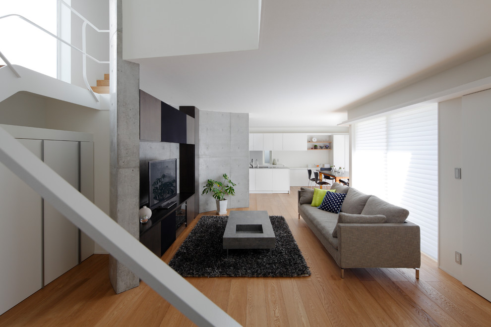 Foto di un soggiorno design di medie dimensioni e aperto con pareti bianche, pavimento in legno massello medio, pavimento marrone e TV nascosta