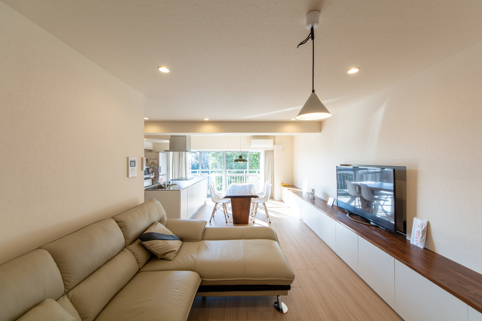 Источник вдохновения для домашнего уюта: открытая гостиная комната в стиле модернизм с белыми стенами, деревянным полом, отдельно стоящим телевизором и бежевым полом