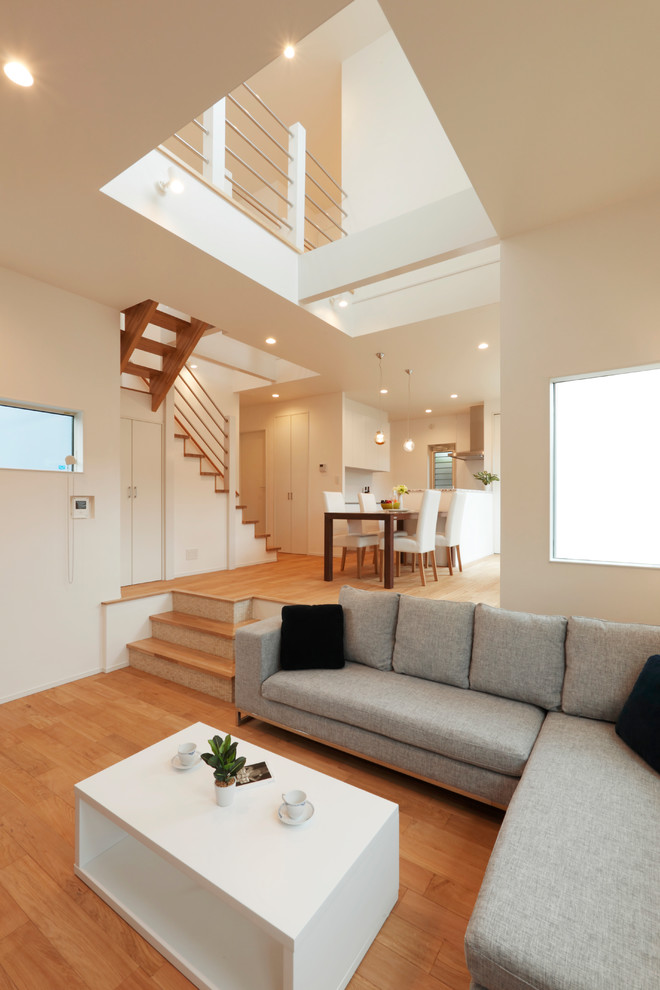 Immagine di un soggiorno minimalista con pareti bianche, pavimento in legno massello medio e pavimento marrone
