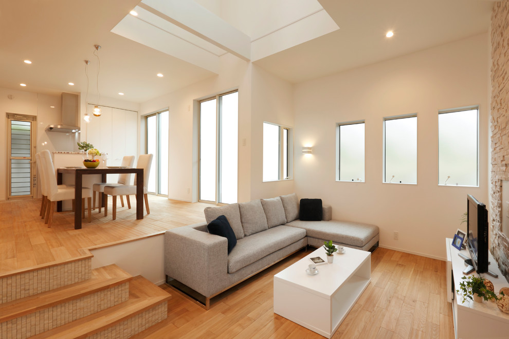 Ejemplo de salón minimalista con paredes blancas, suelo de madera en tonos medios, televisor independiente y suelo marrón