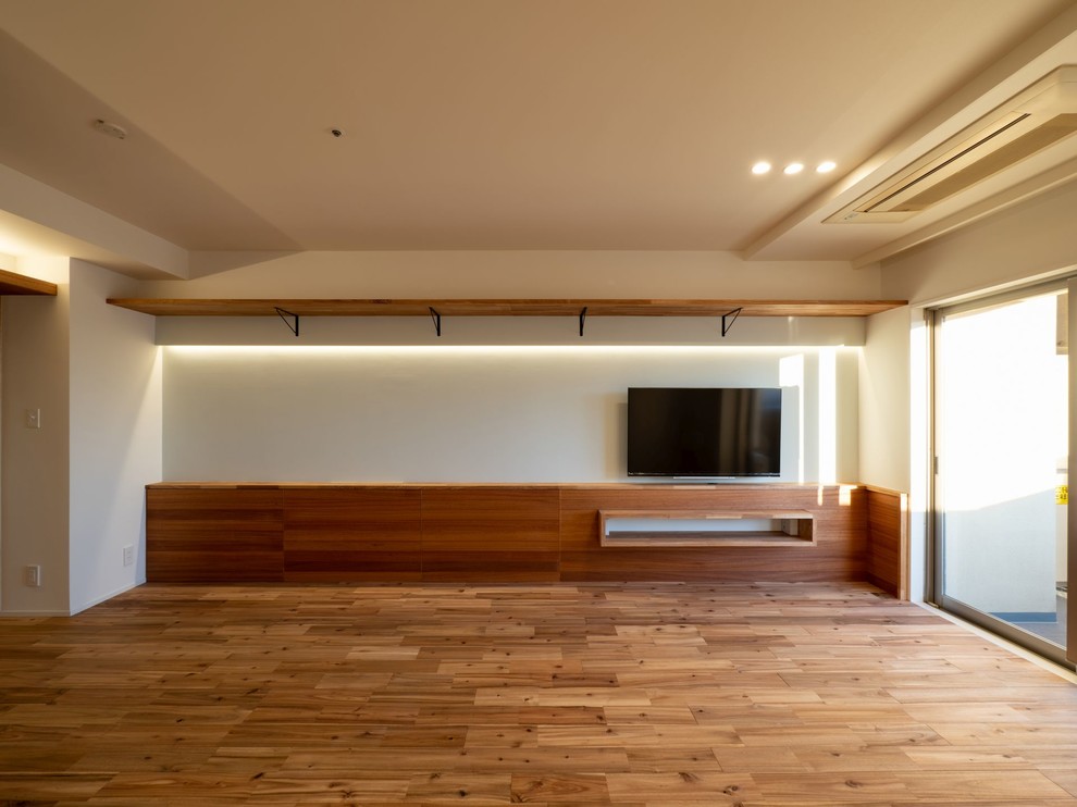 Ispirazione per un soggiorno moderno con pareti blu, pavimento in legno massello medio, TV a parete e pavimento marrone