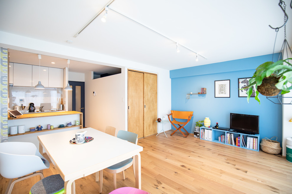 Aménagement d'un petit salon scandinave ouvert avec un mur multicolore, parquet clair et un sol beige.