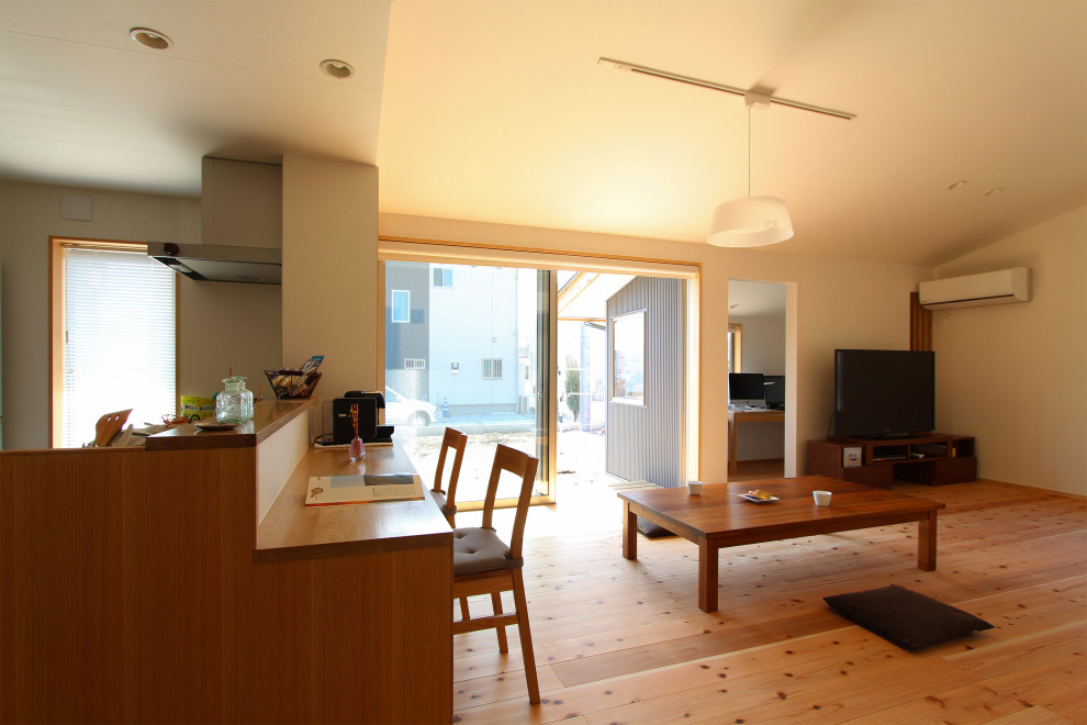 Foto di un soggiorno etnico di medie dimensioni e aperto con pareti bianche, pavimento in legno massello medio, TV autoportante e pavimento marrone