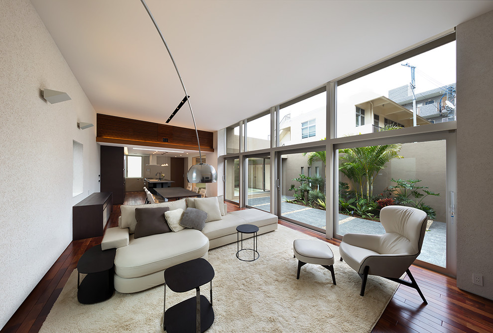Idées déco pour un salon contemporain ouvert avec un mur blanc, parquet foncé et un sol marron.
