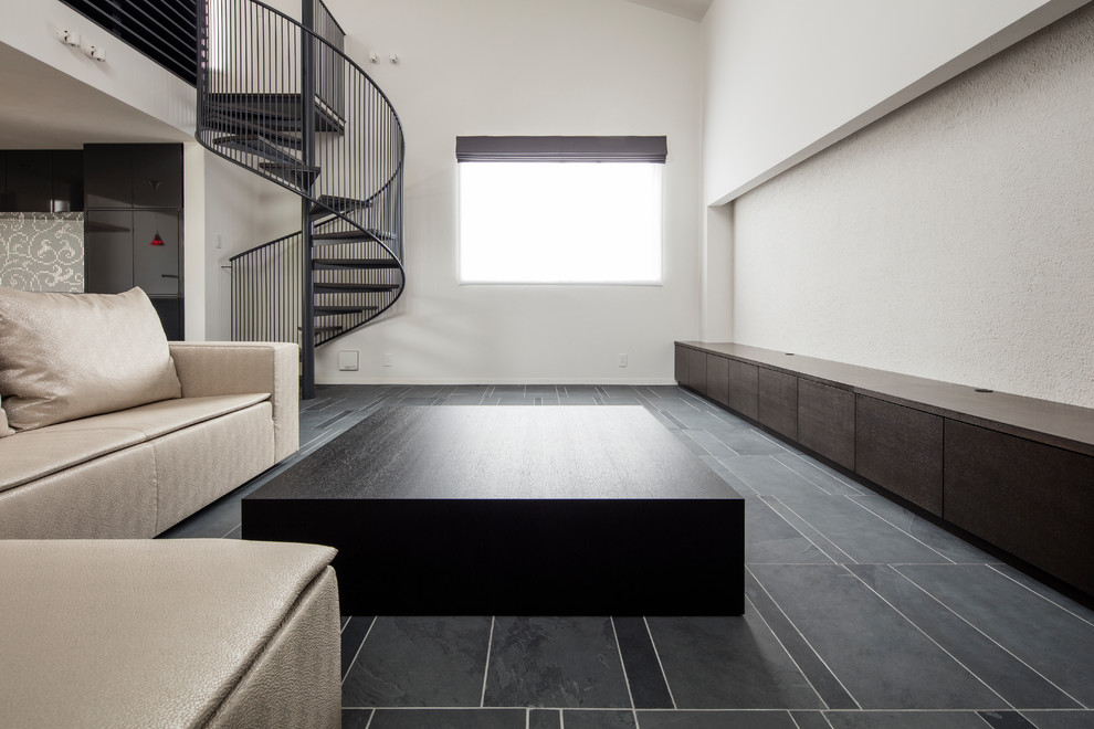 Immagine di un grande soggiorno moderno aperto con pareti bianche, pavimento nero, sala formale, pavimento in ardesia, nessun camino e TV autoportante