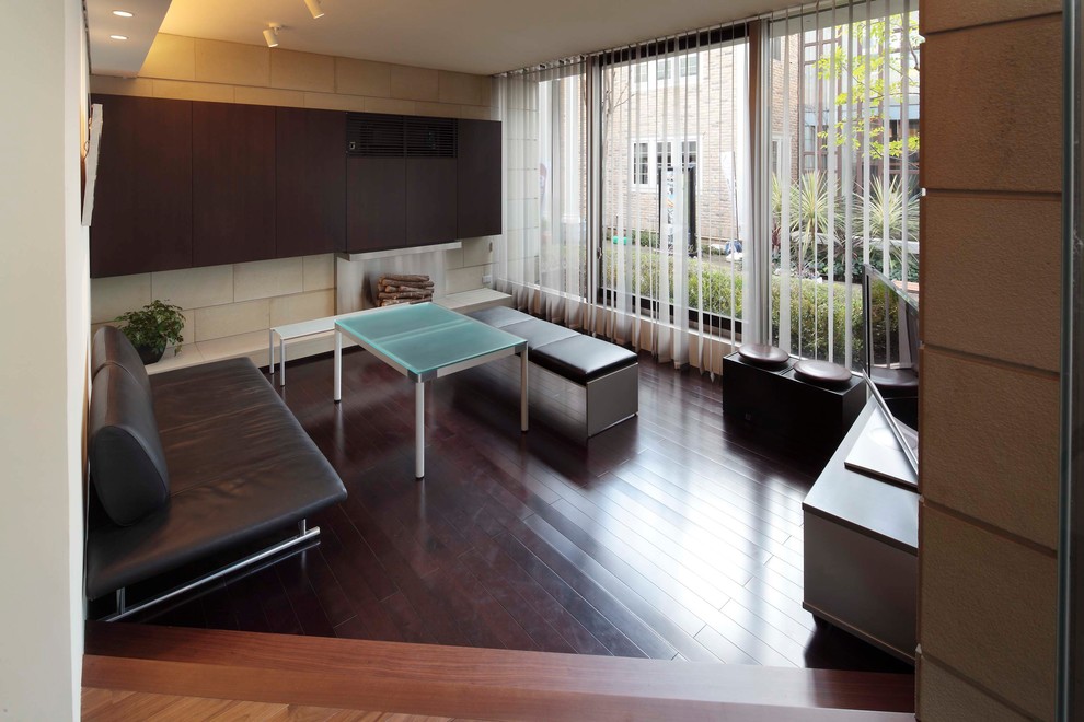 Cette image montre un petit salon minimaliste avec un mur beige, parquet foncé et un sol marron.